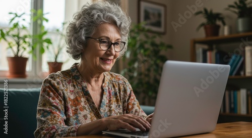 Senior woman using laptop at home, showcasing technology adoption in elderly people