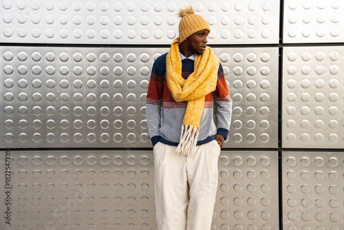 Fashionable individual showcases cozy winter style against modern backdrop in urban setting