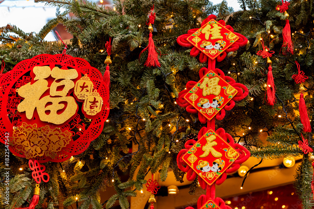 Naklejka premium Chinese-style Christmas tree toys and lights on green Christmas tree. Festive background. Chinese New Year in Moscow. High quality photo