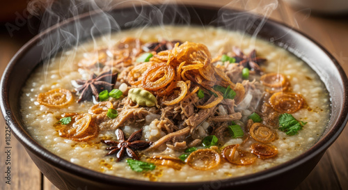 Fototapeta Naklejka Na Ścianę i Meble -  Enjoy the rich, savory flavor of a steaming bowl of delicious Asian congee with tender meat, fried onions, and aromatic spices in a cozy setting