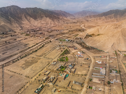Aerial panoramic view of a vast arid valley with a dry riverbed and scattered residential settlements in Cieneguilla near Lima Peru.
