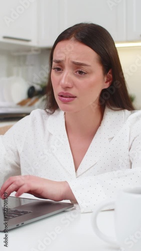 Young woman at home reads laptop result feels upset after lost game or rejected project clicks fast. Caucasian girl on sofa sits at table frowns stares at screen sad mood stress and worry deep sigh