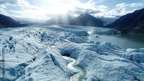 Capturing the immense scale and ancient grandeur of a vast glacier, revealing its deep blue crevasses and rugged ice formations under a dramatic sky. Wide aerial perspective showcasing the?