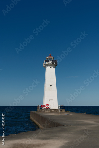 Low angle image of the concrete and stone pier leading to the Sodus Point Lighthouse on Lake Ontario in New York State on a beautiful afternoon
