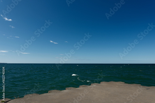 The concrete and stone pier at the Sodus Point Lighthouse on Lake Ontario New York looking out over the lake on a beautiful afternoon