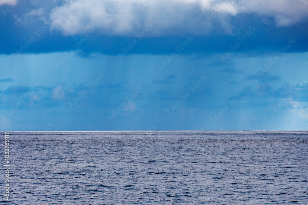 Fototapeta premium 雲の下に激しく降るスコールが見える。 沖縄県那覇市那覇泊港 沖縄の海の玄関口、那覇泊港。 慶良間諸島の座間味島等へゆく高速ジェットフェリー。 クイーンざまみ3号に乗船した。 2025 