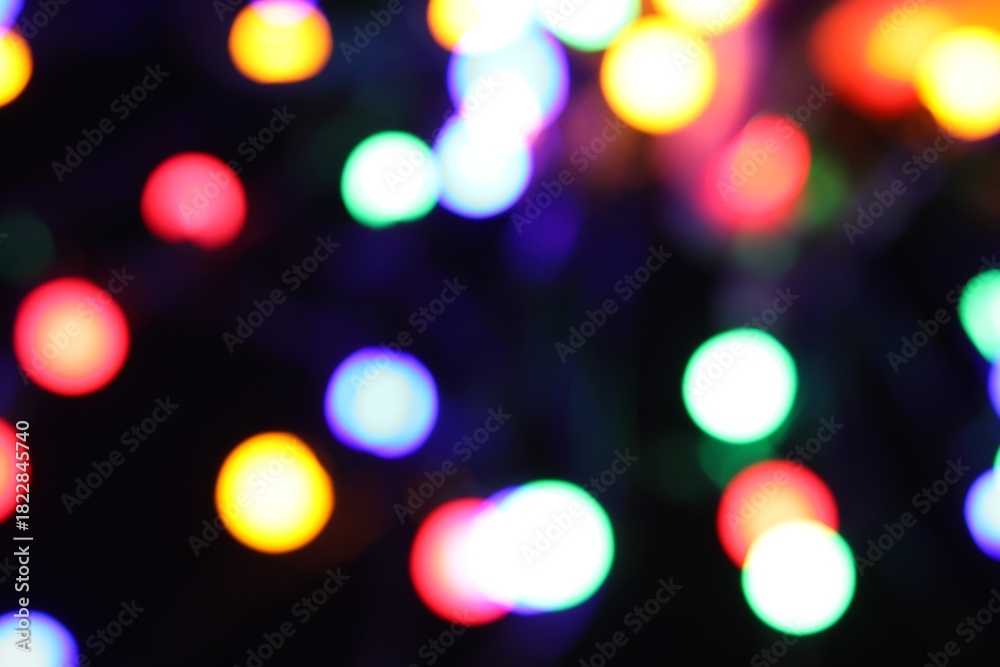 Obraz premium Blurred view of bright Christmas lights on dark background, bokeh effect