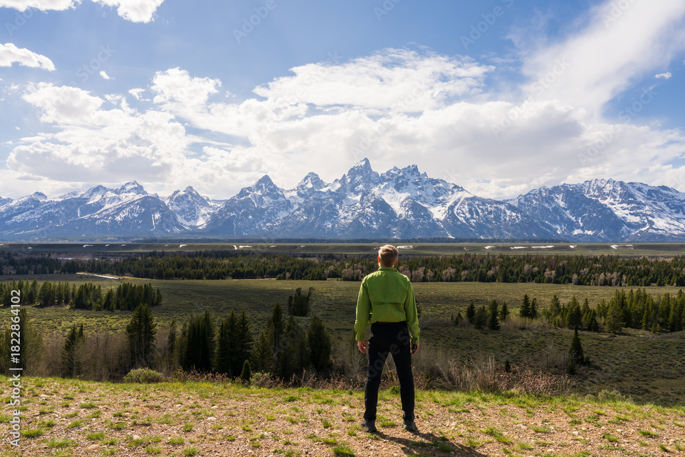 Obraz premium The visitor enjoys a peaceful moment with the iconic Tetons rising above the valley, Early spring travel in Wyoming, USA