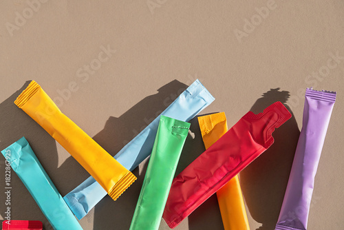 Variety of colorful powder sachets on neutral background with copy space.
