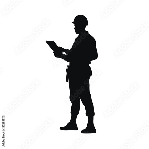 Silhouette of a construction worker holding a tablet and looking at it.
