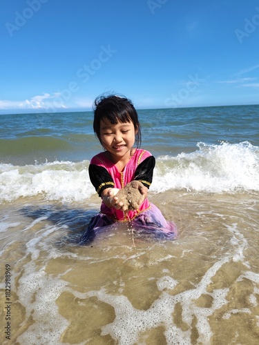 Cute little asian girl playing on the beach 