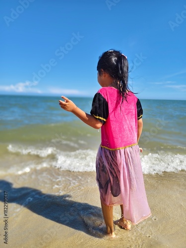 Cute little asian girl playing on the beach 