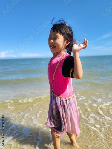 Cute little asian girl playing on the beach 
