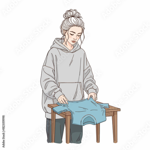 Young woman with a messy bun hairstyle folding a blue shirt.
