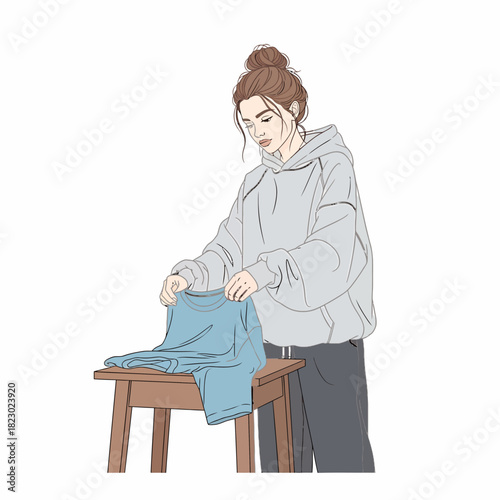 Young Woman Folding Clothes on a Wooden Table.