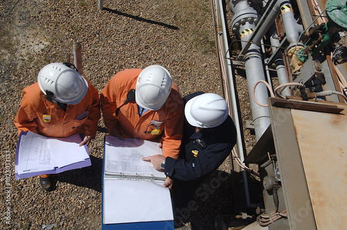 engineers on worksite at refinery discuss refurbishment plans viewed from above.