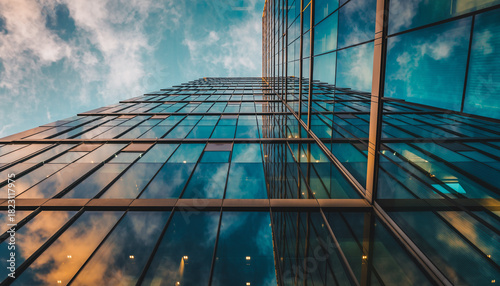 low angle view of modern glass office building reflecting blue sky
