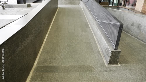 Empty ramp with metal railings for handicapped people near public building entrance . Tilt-up movement with a hand-held.