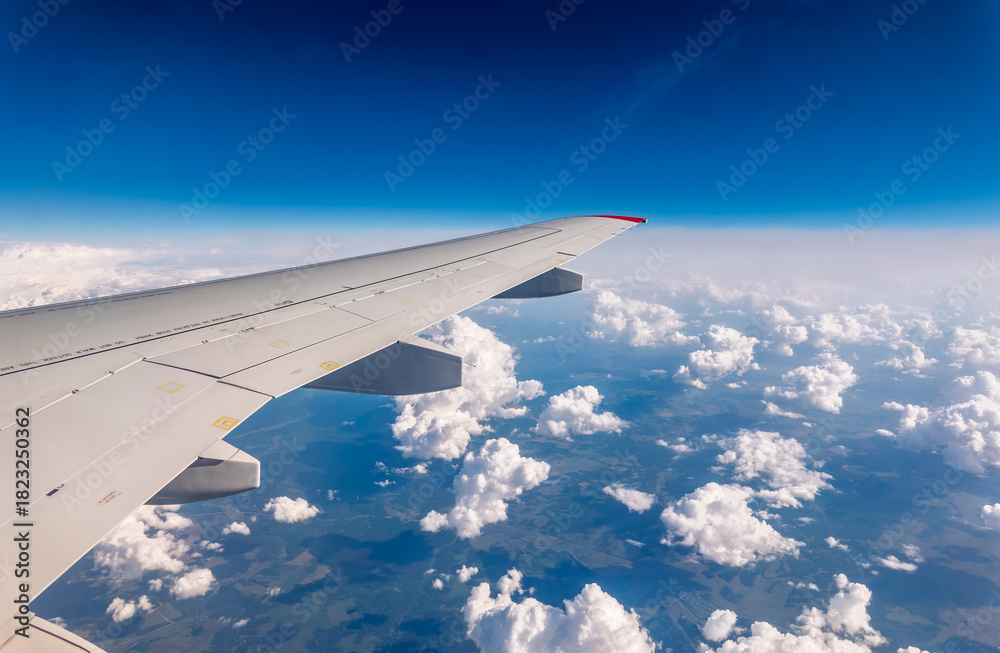 Fototapeta premium View from the airplane window at a beautiful cloudy sky and the airplane wing