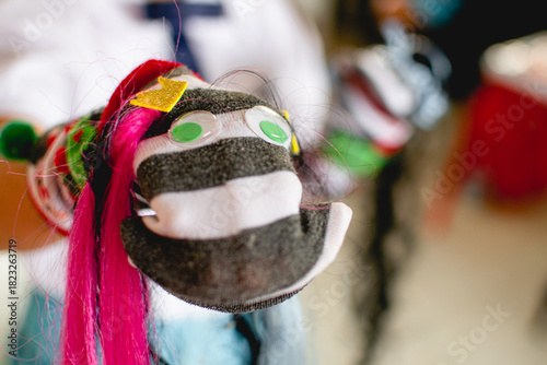 Child holding colorful handmade sock puppet with googly eyes