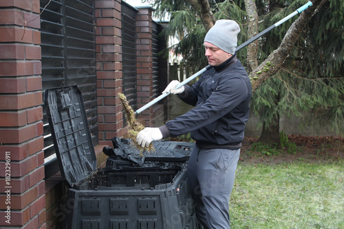 Men's chores, men's daily work tasks. A man puts grass in a composter.