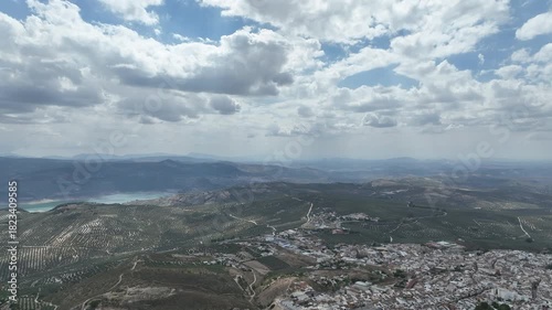 Aerial glides over Andalusian town of Rute over olive orchards to Lake Iznajar