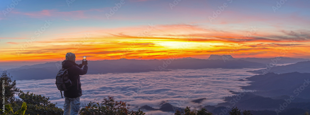 Fototapeta premium Male Hiker with backpack using smartphone taking photos mountains landscape. Sharing travel lifestyle and adventure vacations. Use outdoor modern technology