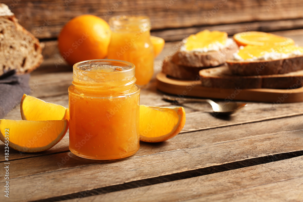 Obraz premium Jar of sweet orange jam on wooden background