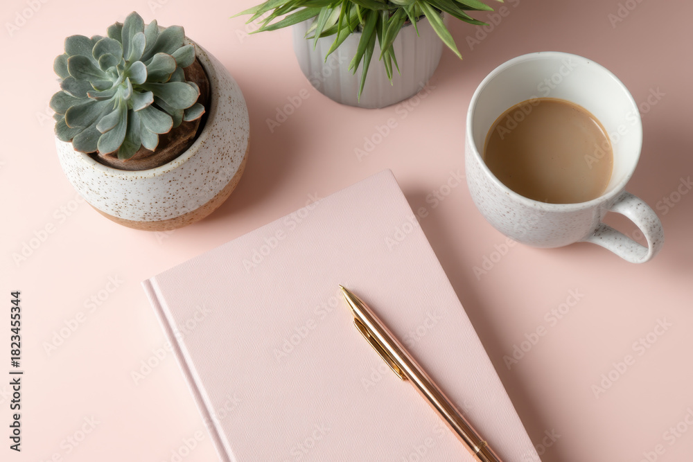 custom made wallpaper toronto digitalPink notebook with gold pen rests on pastel surface, accompanied by coffee cup and two potted plants, creating calm and inviting workspace