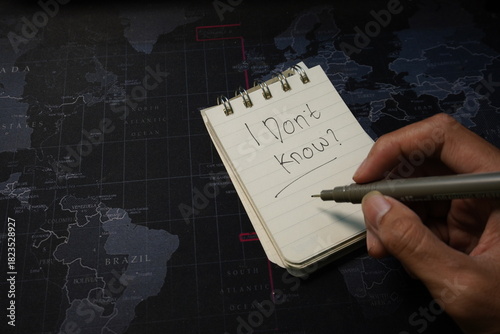 Hand Writing 'I Don't Know' on Notepad Over World Map