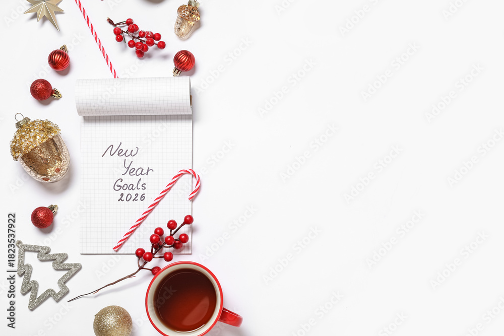 Naklejka premium Notebook with text NEW YEAR GOALS 2026, Christmas decor and cup of tea on white background