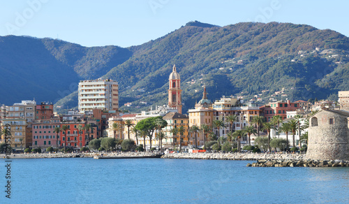 Fototapeta Naklejka Na Ścianę i Meble -  Panoramic view of traditional buildings and structures of Liguria. Mountains of Italy. Mediterranean nature, Europe. Sky, sea, and palm trees of Rapallo. Design backdrop. Tourism and recreation.