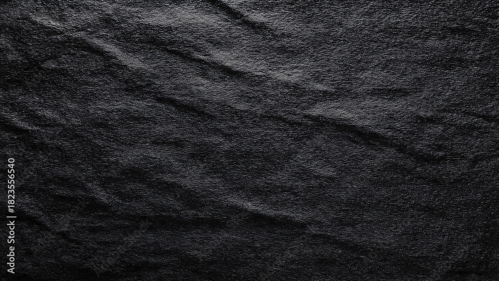 Fototapeta premium Dark wrinkled material with a textured surface and subtle highlights