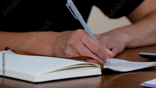Tableau sur toile A person is writing in a notebook
