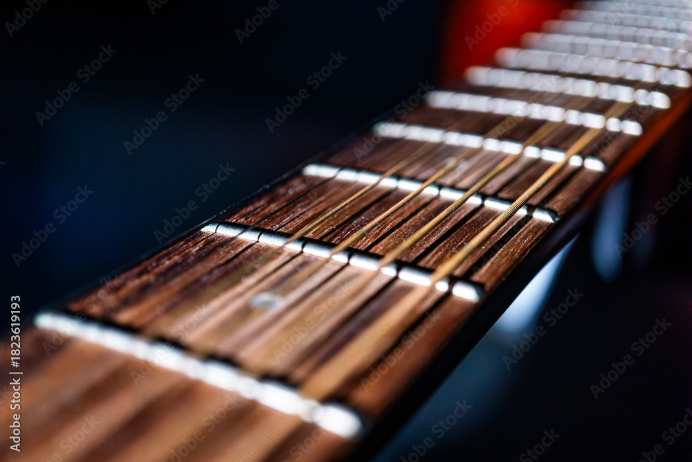 Fototapeta premium Close-up view of an acoustic guitar fretboard, showcasing strings with light brown and dark ends, arranged in parallel and equally spaced The warm wooden fretboard contrasts with the lighter strings