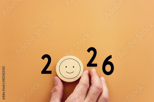 Hand holding wooden circle with the text 2026