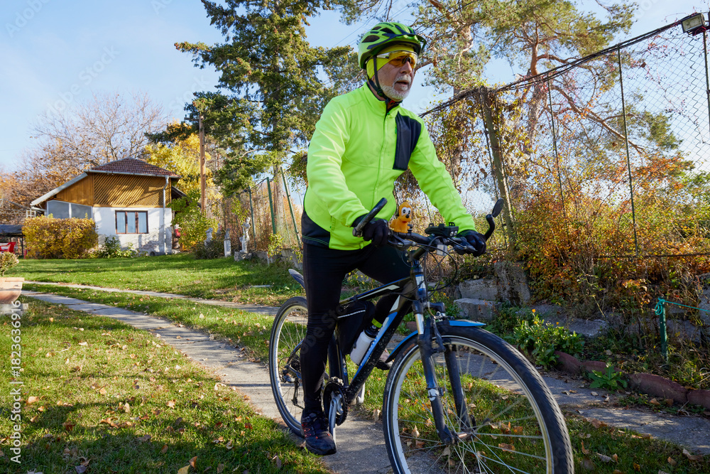 Obraz premium Old man exercising by riding a bicycle on a beautiful autumn day