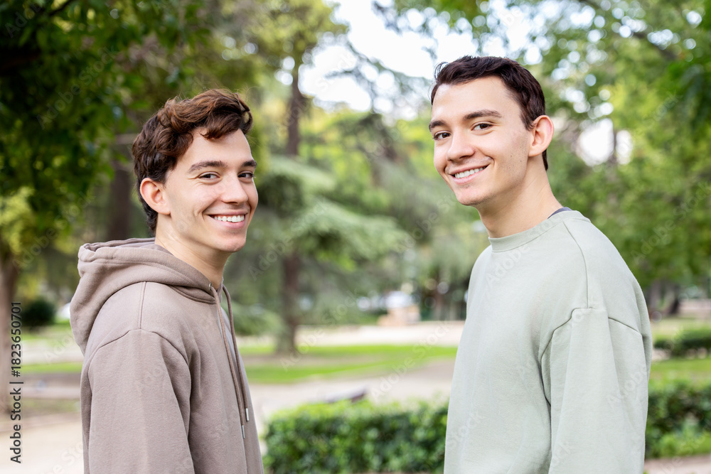 Fototapeta premium Twin brothers smiling at the camera in a green park