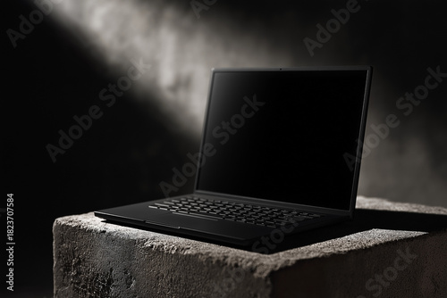 Modern dark laptop staged on textured stone with cinematic lighting