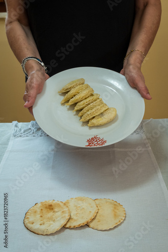 A person holding a porcelain plate containing homemade pasta called culurgiones