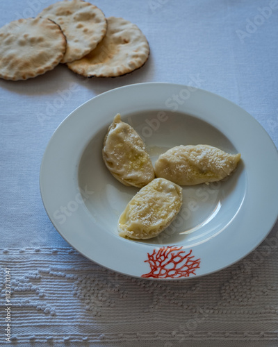 Homemade traditional Sardinian pasta called Culurgiones on a porcelain plate