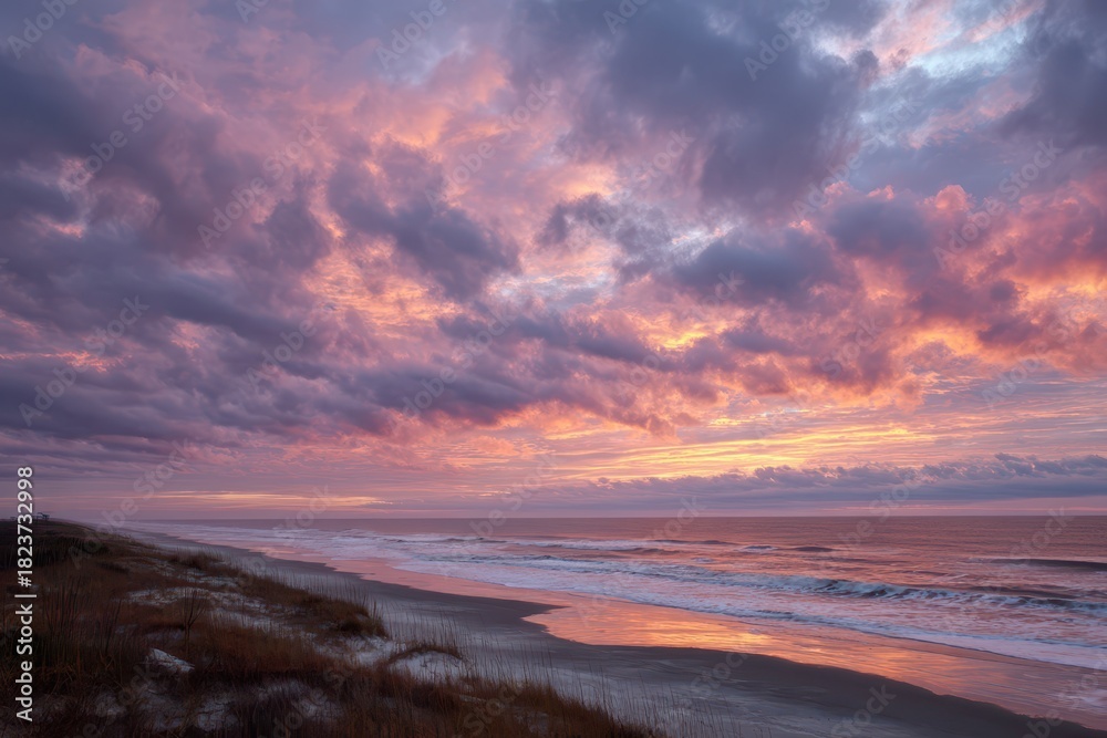 Obraz premium Silhouetted Shore at Dusk Under Halos of Orange and Purple Clouds