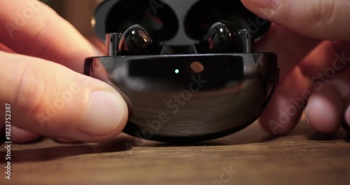 Dark Green TWS Wireless Earbuds Case Snapping Shut Magnetic Click Sound, Fingers Manipulating Gadget Wooden Table Background, Modern Audio Technology Device, Portable Music Accessory Concept