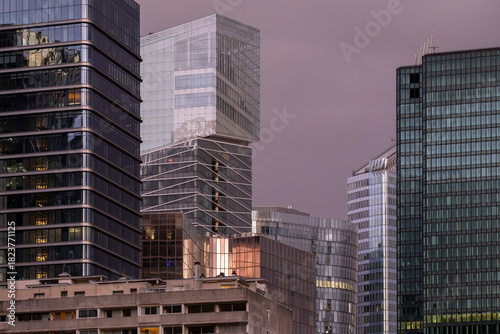 Architecture and skyscraper structures in Paris as warm reflection light strengthens finance and business narratives throughout the urban landscape connected to the corporate district of La Defense.
