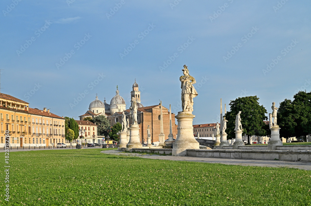 Fototapeta premium Padua, Italy. Pratto della Valle square with two rows of statues (late 18th century), an oval-shaped canal, and bridges. The Basilica of Santa Giustina is in the background.