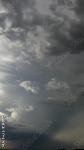 Time-lapse of cumulus clouds forming brewing storm over vast sky, light shifts golden hour to chiaroscuro. Concept of nature's raw power and tension