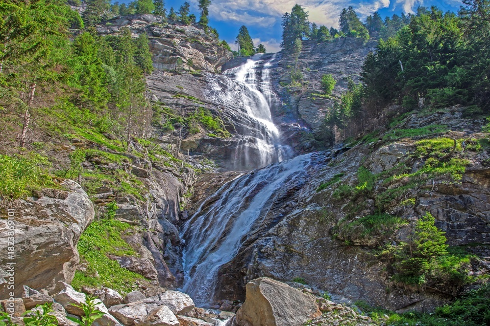 Obraz premium Powerful alpine waterfall cascading down rocky cliff