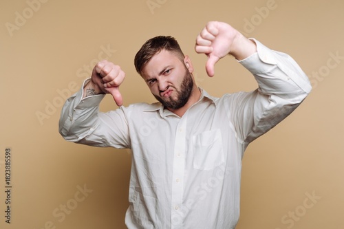Man makes a disapproving gesture while wearing a white shirt against a neutral background