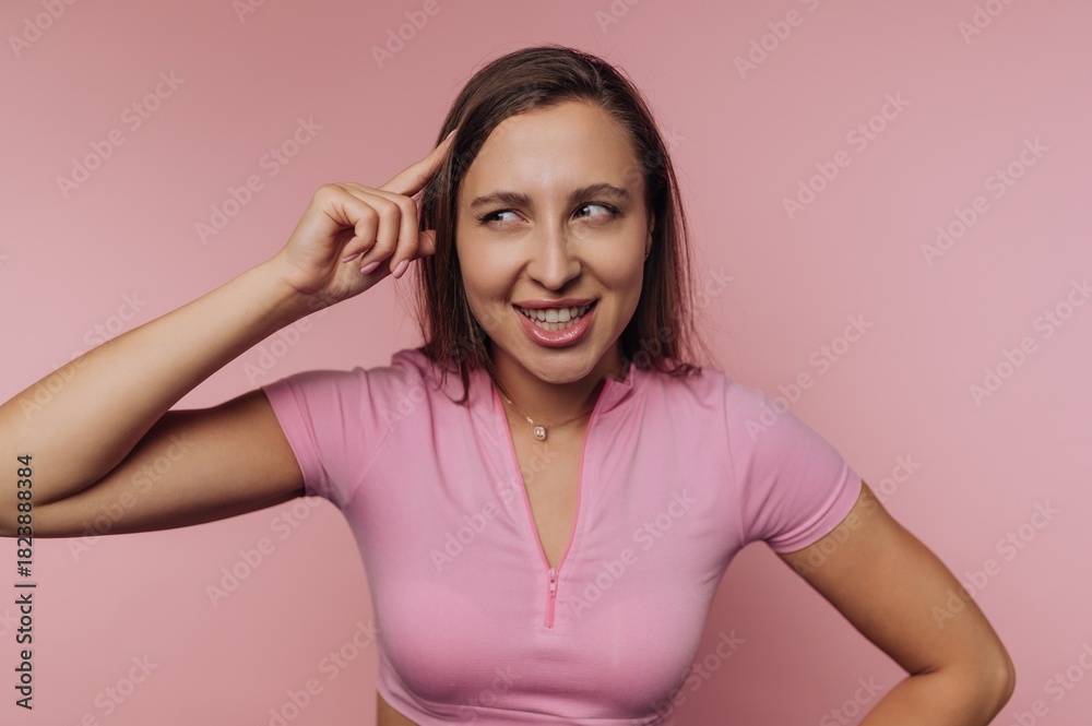 Fototapeta premium Woman with a playful expression poses against a pink background in casual clothing