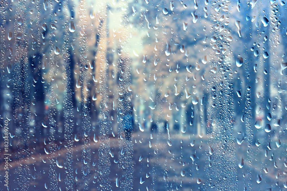 Obraz premium raindrops on glass blurred autumn background trees in the park, seasonal backdrop rainy weather